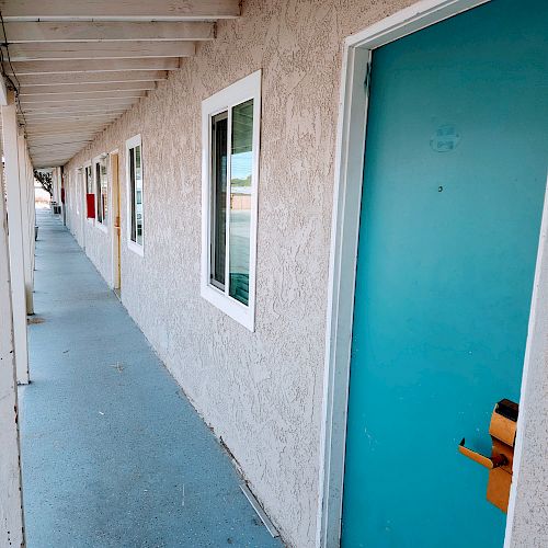 The image shows a row of motel doors and windows along a covered walkway, with the closest door labeled 