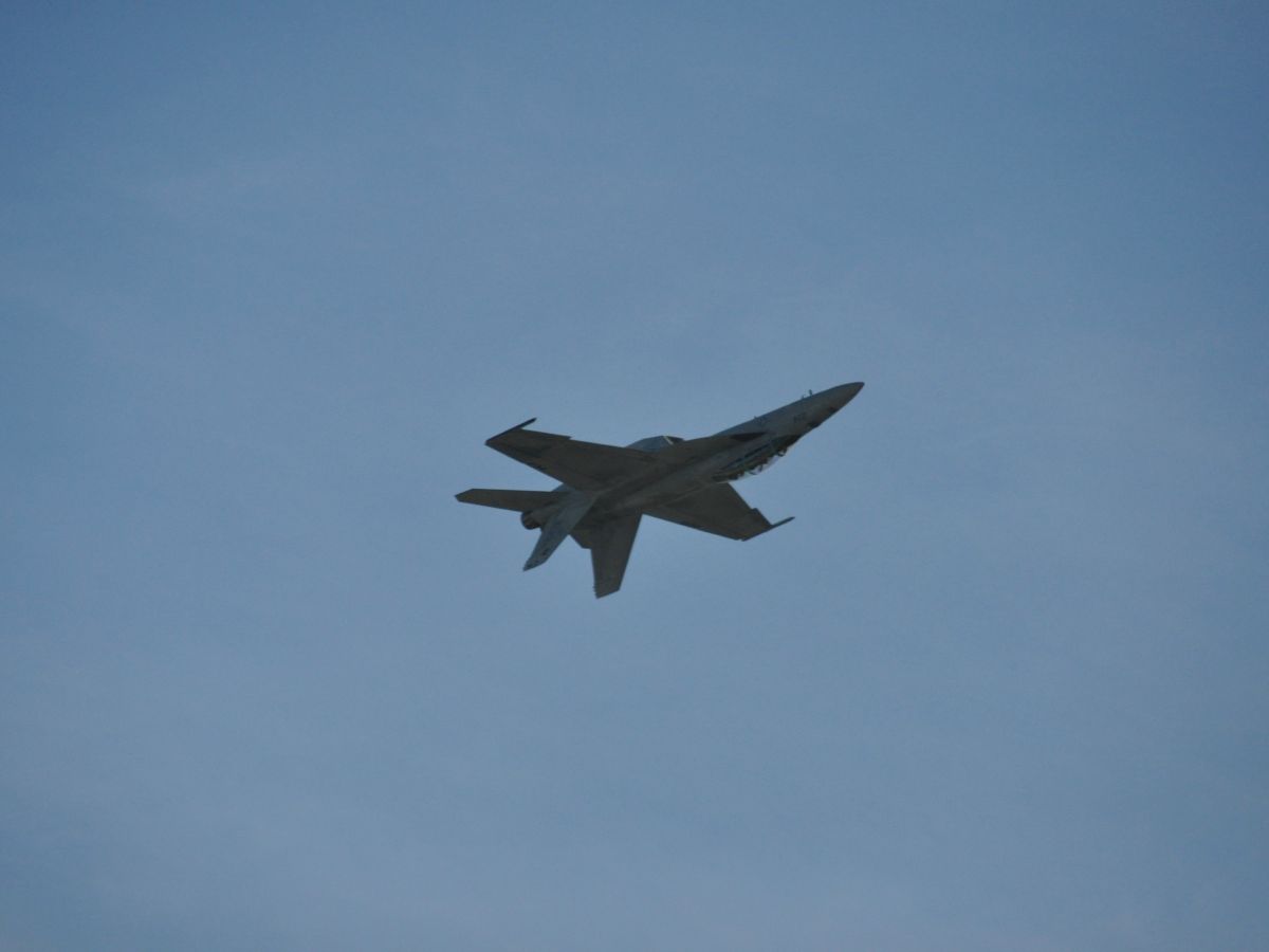 The image shows a jet aircraft flying against a clear blue sky.